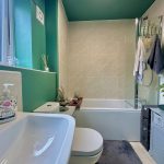 Modern bathroom with green walls and shower.