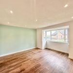 Spacious room with green accent wall and wood flooring.