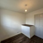 Small white room with wooden flooring.