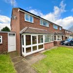 Brick semi-detached house with driveway and green lawn.