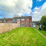 Brick house with garden and wooden fence.