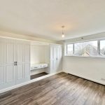 Modern bedroom with wooden floor and large windows.