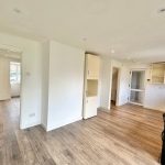 Spacious kitchen with wood flooring and open shelves.