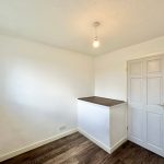 Minimalist white room with wooden flooring and door