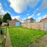 Suburban backyard with grass and small outbuilding.