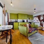 Cosy living area with green kitchen cabinets.