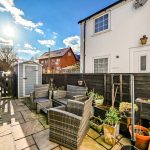 Sunny patio with garden furniture and shed.