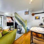 Cosy living room with green sofa and staircase.