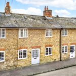 Stone terraced houses with chimneys and white doors.