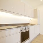 Modern kitchen with sleek white cabinetry and appliances.