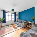 Contemporary living room with blue accent wall and plants.