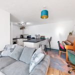 Modern open-plan living room with sofa and kitchen.