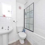 Modern white bathroom with shower and sink.