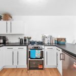 Modern kitchen with white cabinets and black countertops.