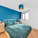 Modern bedroom with blue accent wall and green bedding.