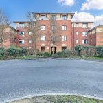 Red-brick residential building with trees.