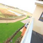 Balcony view of garden and path beside pond.