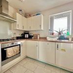 Modern kitchen with white cabinets and appliances.