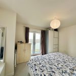 Bright bedroom with wardrobe and balcony doors.