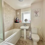 Modern bathroom with bathtub and white tiles.