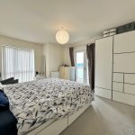 Modern bedroom with white furniture and double bed.