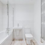 Modern white bathroom with bathtub and towel radiator.