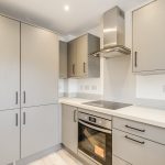 Modern kitchen with grey cabinets and built-in cooker.