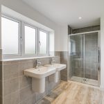 Modern bathroom with double sinks and shower.