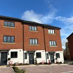 Modern brick townhouses with parking and clear sky.