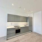 Modern kitchen with grey cabinets and wood flooring.