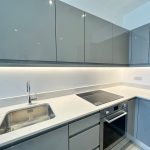 Modern kitchen with grey cabinets and sleek surfaces.