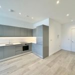 Modern kitchen with grey cabinets and wood flooring.