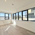 Bright empty room with large windows and wooden floor.