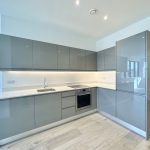 Modern grey kitchen with appliances and wooden floor.