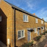 Newly constructed brick terraced houses with gardens.