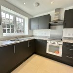 Modern kitchen with dark cabinets and marble countertops.