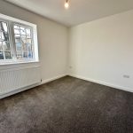 Empty room with large window and radiator.