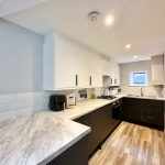 Modern kitchen with wooden flooring and white cabinets.