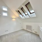 Bright attic room with skylights and neutral decor.