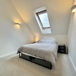 Modern attic bedroom with skylight and grey bedding.