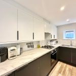 Modern kitchen with appliances and wooden floor.