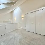 Spacious loft with skylights and white closet doors.