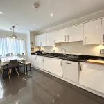 Modern kitchen with white cabinets and dining table.